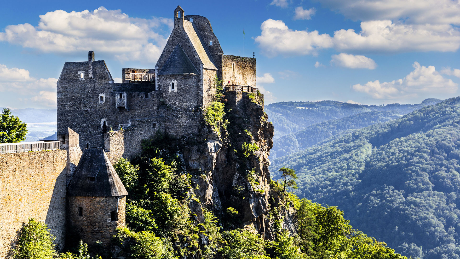 Medieval castle ruin on a rocky crag above forested hills