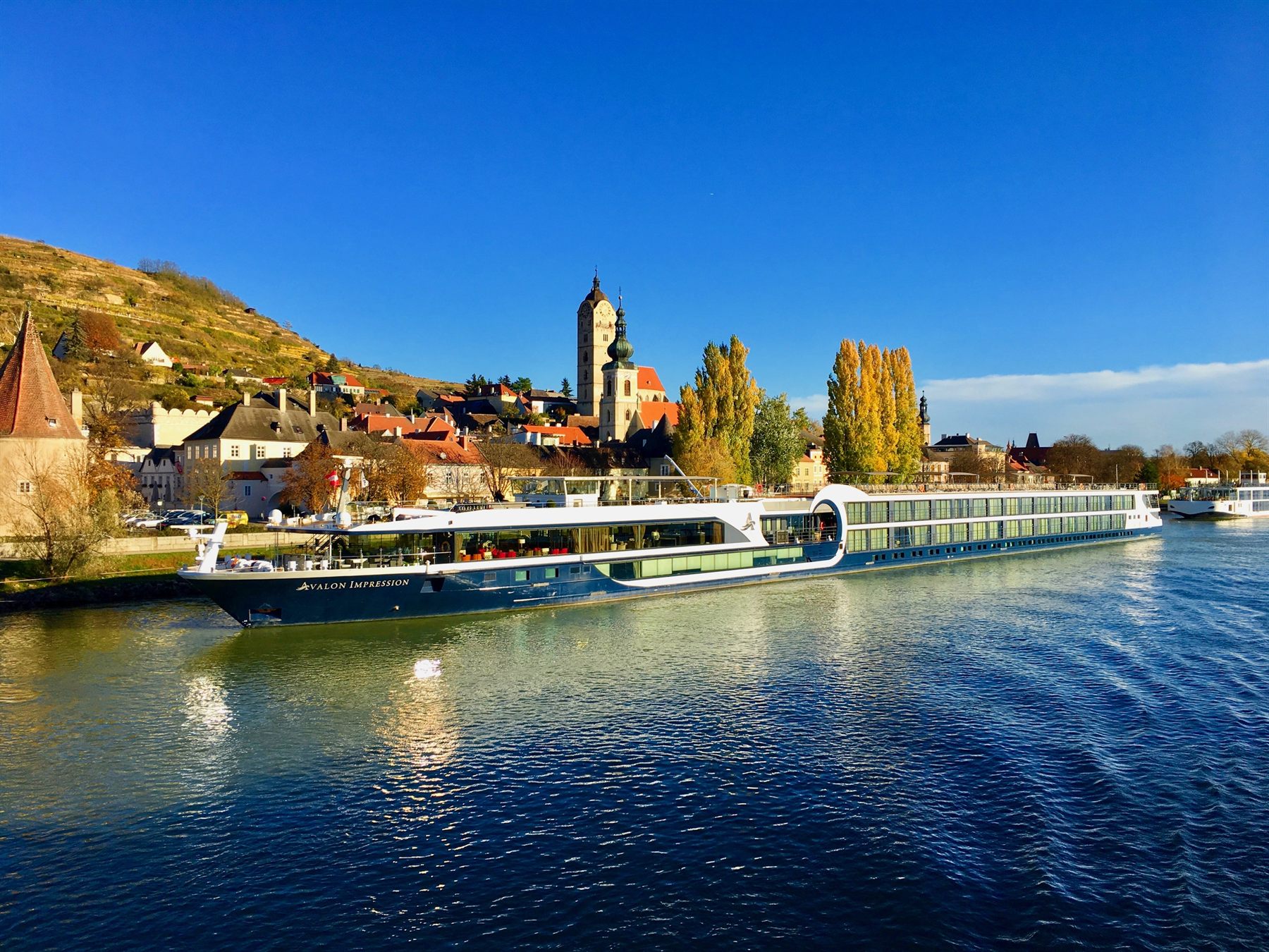 River cruise ship moored below a hillside town with a church tower on the Danube